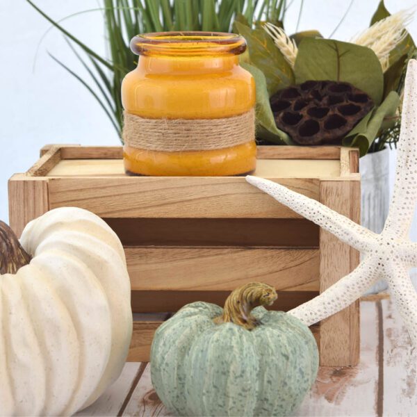 A wooden crate with pumpkins, a starfish, and a candle.