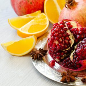 Pomegranate and orange slices on a silver plate.