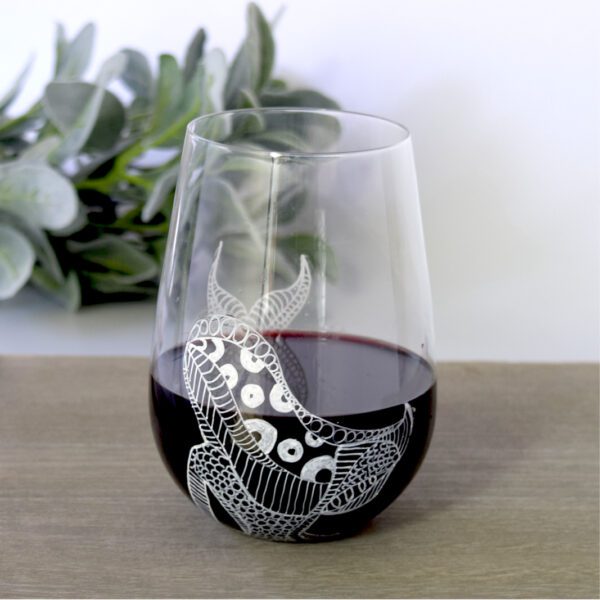 A hand-painted Le Blanc wine glass with a zodiac design on it.