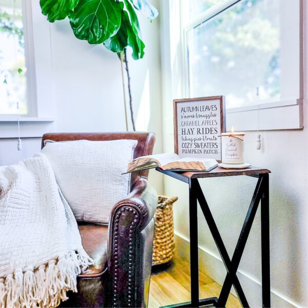 A living room with a chair and a plant on a side table.