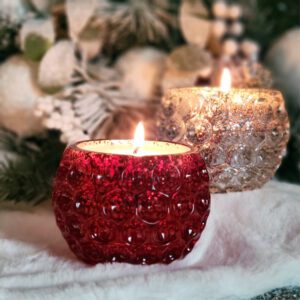 Two candle holders with a christmas tree in the background.