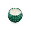 A candle in a green glass bowl on a white surface.