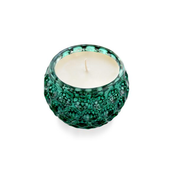 A candle in a green glass bowl on a white surface.