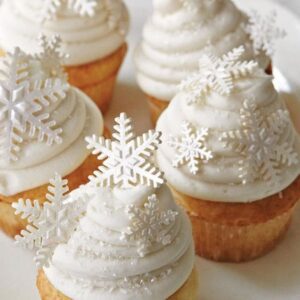 Cupcakes with white frosting and snowflakes on a plate.