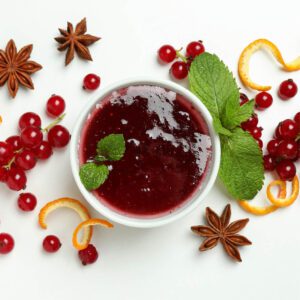 A bowl of cranberry juice with oranges and spices.