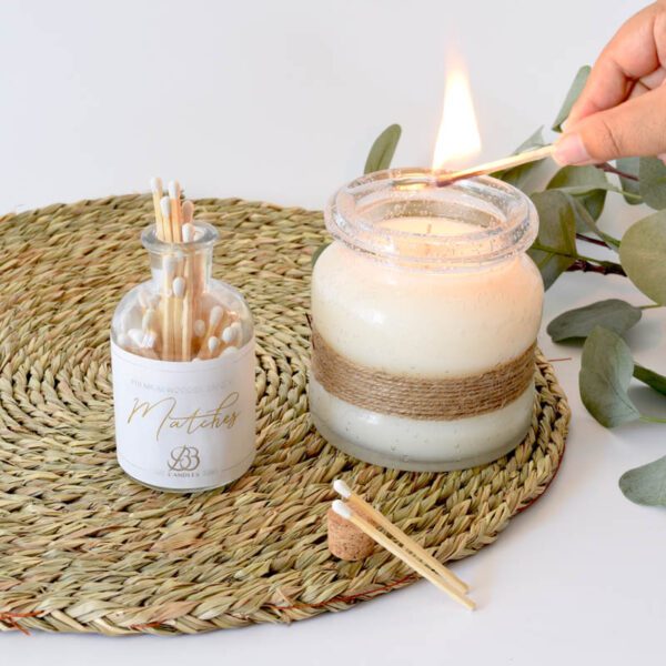 A person is holding a candle and matches on a rug.