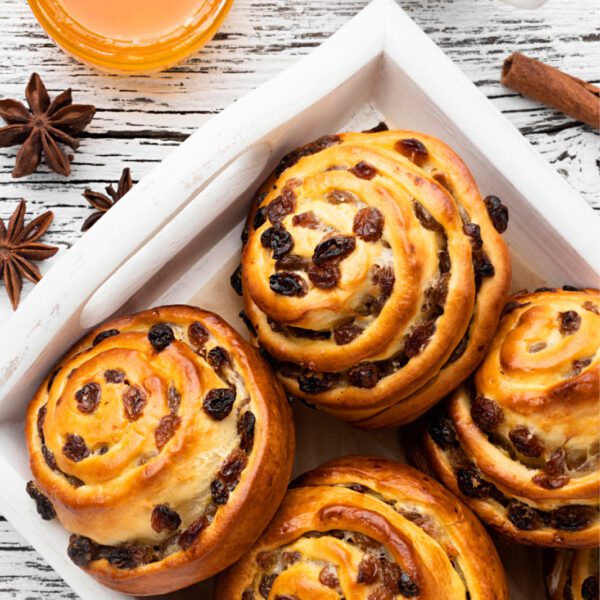 Buns with raisins and spices on a wooden table.