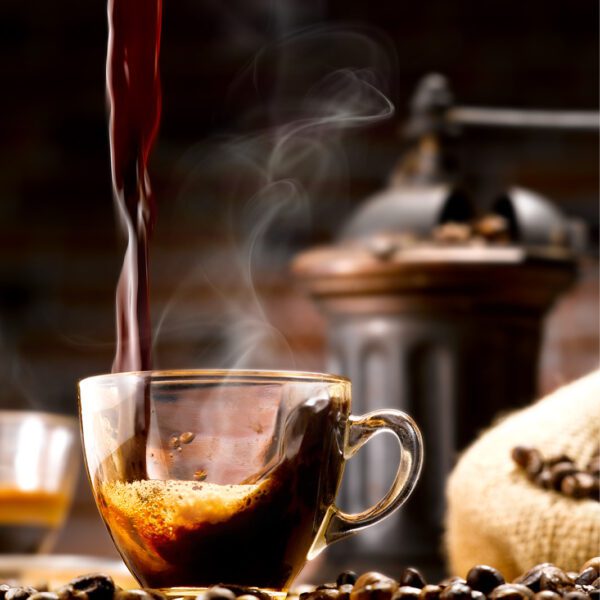 A cup of coffee is being poured into a cup of coffee beans.