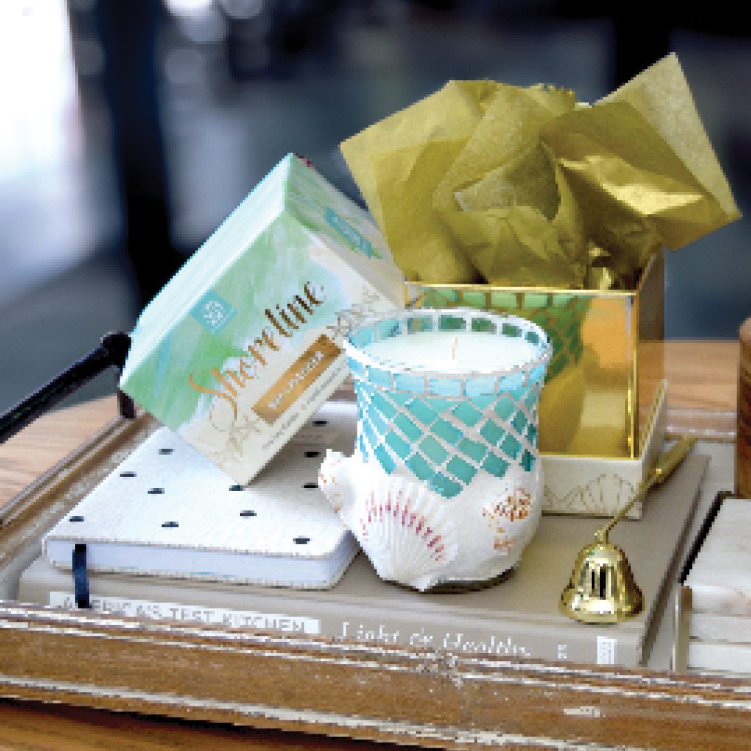 A scented candle placed atop a tray, along with a book for home decor.