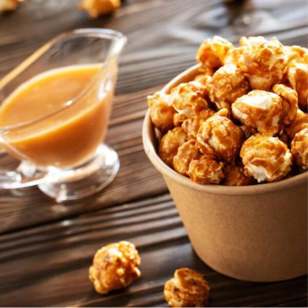 Rich caramel popcorn in a brown paper cup with a smooth caramel dip on a wooden table, capturing the essence of salted caramel